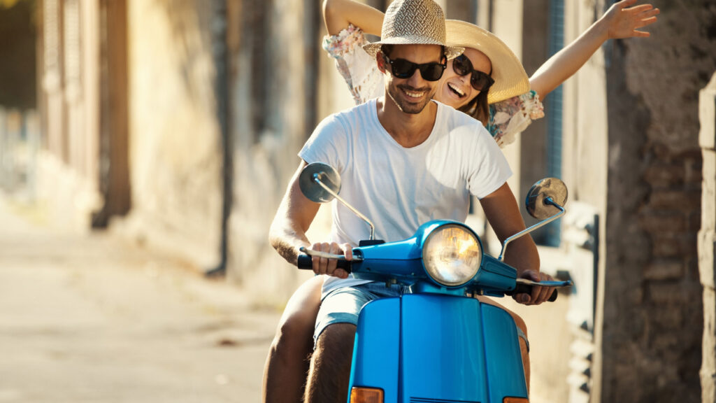 Couple on a scooter bike driving through city streets.