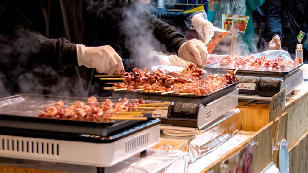 cooks prepare meat on skewers at a market in Tokyo, Japan